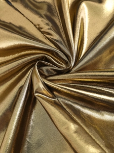 Macro detail of champagne gold metallic fabric with smooth texture and luxury drape