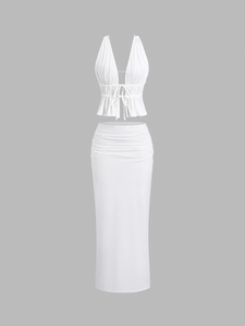 Detailed view of white two-piece set featuring halter neck top and ruched maxi skirt