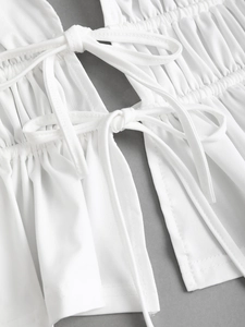 Detailed view of white milk silk top featuring elegant smocked pleats and ribbon bows