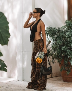 Détail d'un haut dos nu noir à licou associé à un pantalon taille haute à imprimé léopard