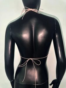 Dettaglio del top rosa a rete con strass e fiocco intrecciato sul retro su un manichino
