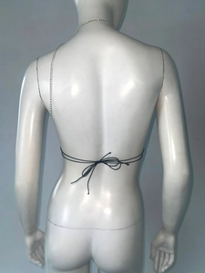 Détail de l'accessoire de corps en chaîne argentée avec bretelles noires sur le dos du mannequin