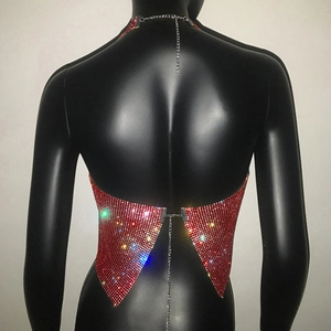 Dettaglio del top all'americana in rete di strass rossi con catene e lacci incrociati