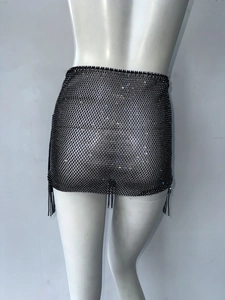 Detail eines schwarzen Netzhaut-Minirocks mit glitzernden Strasssteinen und Fransensaum