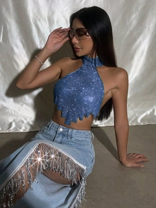 Detail von blauem Pailletten-Halter-Top mit Glanz und silbernen Fransen am Jeansrock