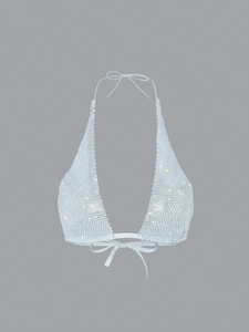 Macro detail of the sparkling rhinestone mesh and halter ties on the silver glitter top