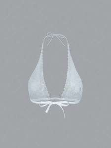 Detail of white mesh halter top featuring intricate hollow-out texture and bow tie closure