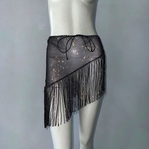 Détail de mini-jupe en résille noire avec strass brillants et ourlet à franges