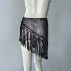Détail d'une mini-jupe en maille strassée noire avec de longues franges et un ourlet asymétrique