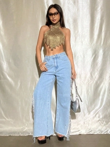 Detailansicht eines sexy goldenen Neckholder-Tops mit hellblauer Fransen-Jeans