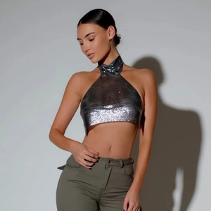 Détail macro du tissu en maille métallique argentée et design dos nu sur le crop top