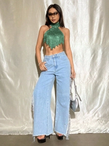 Detailaufnahme von grünem Pailletten-Neckholder-Top und Jeans mit Fransenverzierung