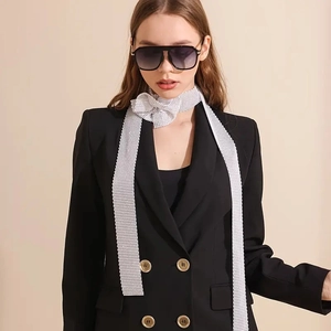 Détail d'une écharpe en maille strass argentée nouée en boucle sur un blazer noir élégant