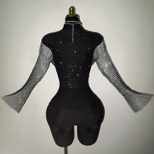 Macro detail of black fishnet bodysuit featuring sparkling rhinestones and flared sleeves