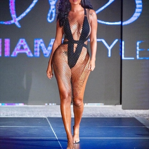 Dettaglio della tuta in rete nera con strass e ritagli sulla passerella di alta moda