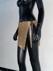 Détail de mini-jupe en strass dorés avec maille métallique étincelante et chaîne ajustable