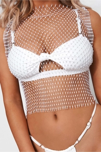 Dettaglio del crop top in rete bianca con strass scintillanti e decorazioni di perle