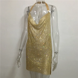 Détail de la robe courte en maille dorée avec fente haute et strass brillants