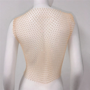 Dettaglio del gilet a rete oro champagne con strass scintillanti sul retro di un manichino