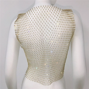 Dettaglio del gilet in rete metallica dorata con strass scintillanti e motivo a rombi