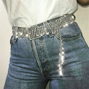 Détail d'une ceinture en strass avec des pompons scintillants sur un jean en denim