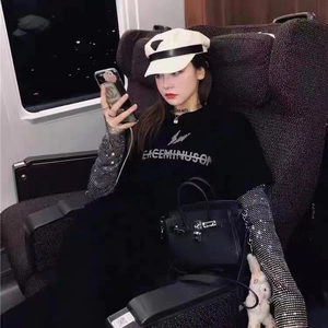 Détail de la manche en résille argentée à strass superposée sous un t-shirt graphique noir