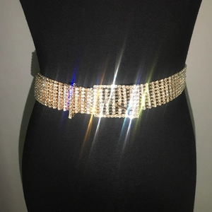 Détail d'une ceinture dorée ornée de strass brillants avec une boucle carrée élégante