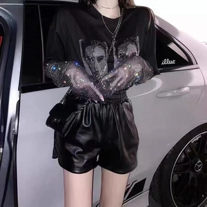 Détail de manches longues en résille strassée avec t-shirt noir imprimé et short en cuir