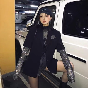 Détail de manches en résille avec strass brillants portées avec un blazer noir élégant