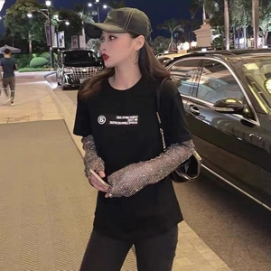 Détail de manches en maille strassée scintillante avec un t-shirt noir imprimé à la mode