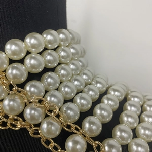 Détail d'une chaîne de corps multicouche en perles et maillons dorés sur fond noir
