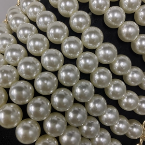 Gros plan sur des perles blanches multicouches avec détails dorés sur tissu noir