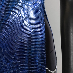 Macro detail of royal blue metal sequins and silver chain link on a slit party dress