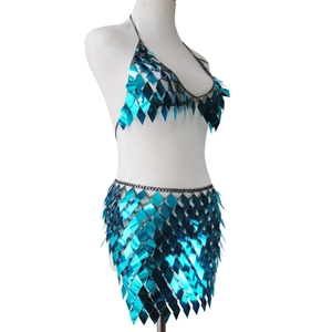Detail of teal rhombus sequins and grey metal chains on backless party outfit