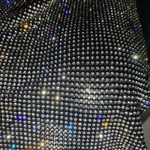 Vue macro détaillée de strass argentés denses sur tissu mesh noir montrant l'éclat brillant