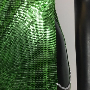 Close-up of green metallic sequins and silver chain detail on a party dress