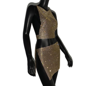 Détail du tissu en maille strass dorée sur le haut dos nu et la mini-jupe asymétrique