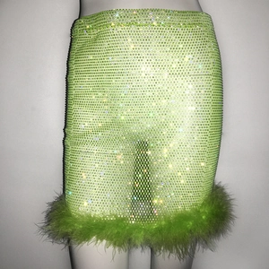 Détail de la mini-jupe vert néon avec strass brillants et bordure en plumes élégantes