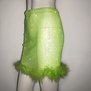 Détails macro de paillettes vert néon et de plumes douces sur une mini-jupe de soirée