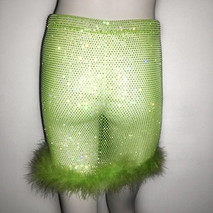 Détail d'une mini-jupe vert citron avec des strass brillants et bordure en plumes douces