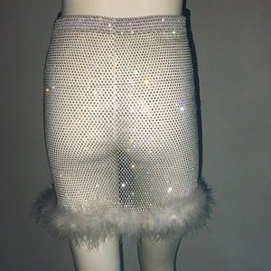 Détail d'une jupe en mesh blanc ornée de strass brillants et d'une bordure en plumes
