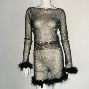 Detailaufnahme von schwarzem Netzkleid mit funkelnden Strasssteinen und Federsaum
