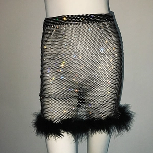 Détail de la mini-jupe en maille noire avec strass scintillants et plumes élégantes