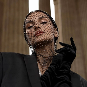 Fashionable black mesh headscarf with sparkling rhinestones worn by a model in a luxury setting