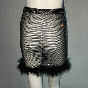 Détail de la mini-jupe en résille noire avec strass brillants et bordure en plumes noires