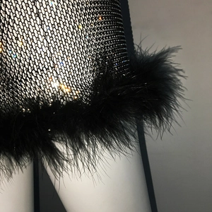 Gros plan détaillé de strass étincelants sur résille noire et bordure en plumes noires