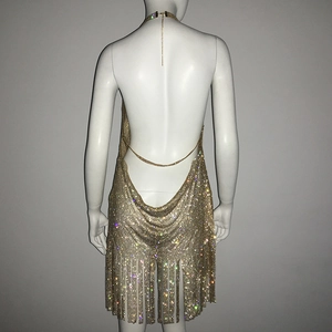 Détail d'une robe en maille strass dorée avec dos nu et ourlet à franges élégantes