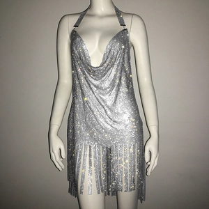 Détail de la robe en maille strass argentée avec col en V profond et ourlet à franges