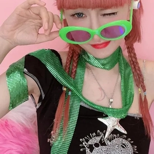 Close-up of green metallic sequin scarf and Y2K star pendant necklace on a model