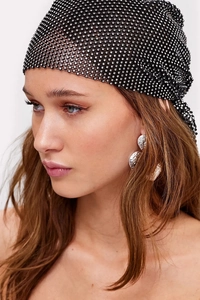 Close-up of black fishnet cap with sparkling rhinestones and silver metallic earrings